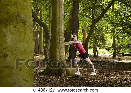 Stock Photo - Jogger stretching in forest. Fotosearch