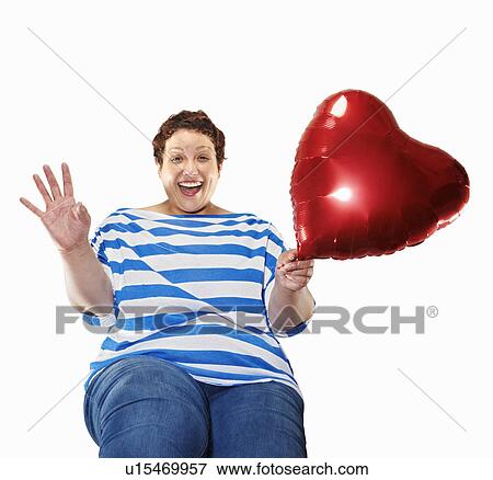 Stock Photo - Large woman carrying heart balloon. Fotosearch