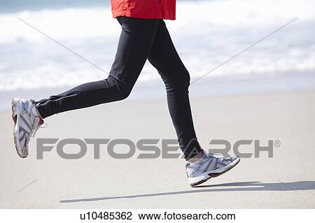 Stock Image - Legs running on beach. Fotosearch