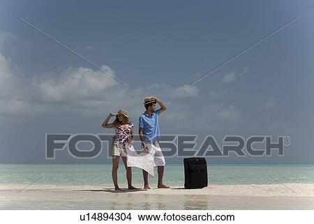 Picture - Lost couple holding map on beach. Fotosearch