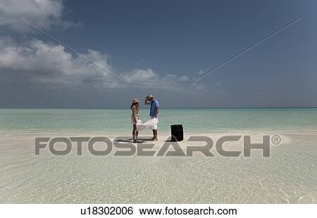 Stock Photograph - Lost couple reading map on beach. Fotosearch
