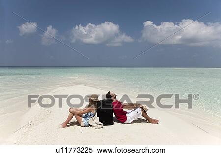 Stock Photography - Lost couple sitting together on beach. Fotosearch