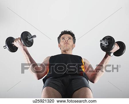 Stock Image - Low angle view of man lifting weights. Fotosearch
