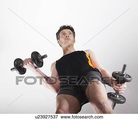 Low angle view of man lifting weights View Large Photo Image Stock Photo - Low angle view of man lifting weights. Fotosearch