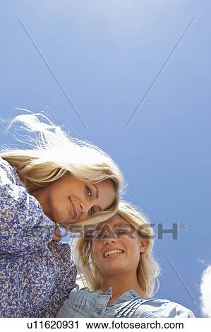Low angle view of sisters hugging View Large Photo Image Stock Image - Low angle view of sisters hugging. Fotosearch