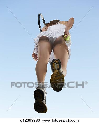 Stock Photograph - Low angle view of woman playing tennis. Fotosearch