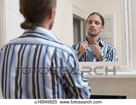 Man adjusting his shirt in mirror View Large Photo Image Stock Photography - Man adjusting his shirt in mirror. Fotosearch