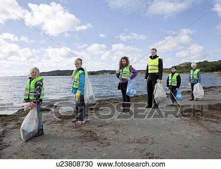 Stock Image - Man and children cleaning beach. Fotosearch