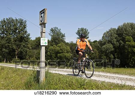 Stock Image - Man biking on dirt road. Fotosearch