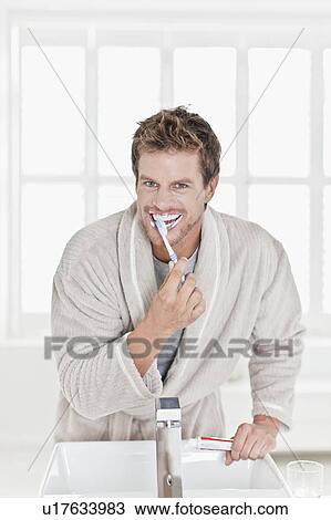 Stock Image - Man brushing his teeth in bathroom. Fotosearch