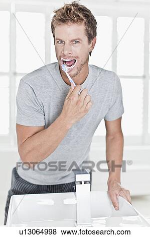 Man brushing his teeth in bathroom View Large Photo Image Stock Photo - Man brushing his teeth in bathroom. Fotosearch