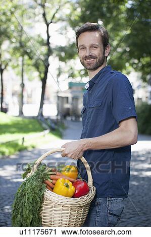Stock Image - Man carrying basket of vegetables. Fotosearch