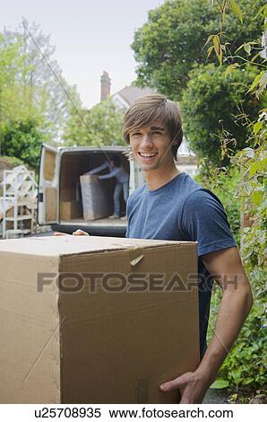 Stock Photography - Man carrying cardboard box in new home. Fotosearch