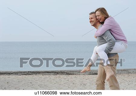 Man carrying girlfriend on beach View Large Photo Image Stock Photo - Man carrying girlfriend on beach. Fotosearch