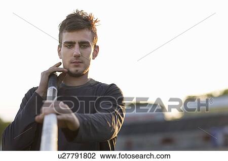Stock Image - Man carrying pole outdoors. Fotosearch