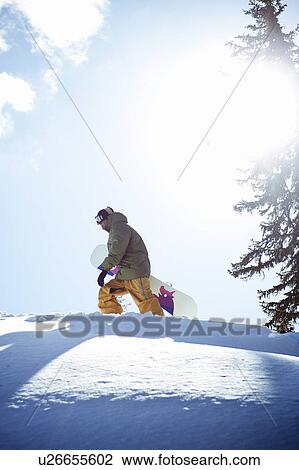 Man carrying snowboard on mountainside View Large Photo Image Stock Image - Man carrying snowboard on mountainside. Fotosearch