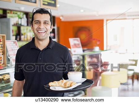 Stock Image - Man carrying tray of food in cafe. Fotosearch