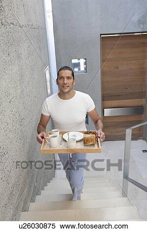 Stock Photography - Man carrying tray of food up stairs. Fotosearch