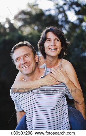 Man carrying woman piggyback outdoors View Large Photo Image Stock Photo - Man carrying woman piggyback outdoors. Fotosearch