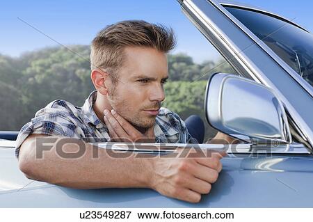 Stock Photo - Man checking himself in car side mirror. Fotosearch