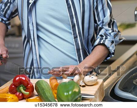 Stock Photo - Man chopping vegetables in kitchen. Fotosearch