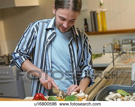 Man chopping vegetables in kitchen View Large Photo Image Stock Photograph - Man chopping vegetables in kitchen. Fotosearch