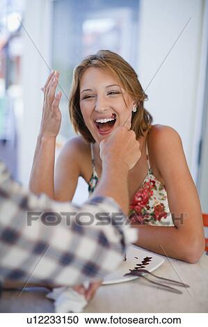 Stock Image - Man cleaning chocolate off woman’s face. Fotosearch