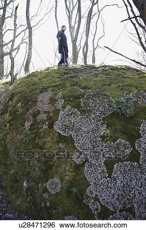 Stock Photograph - Man climbing mossy boulder. Fotosearch