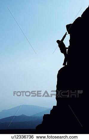 Stock Photograph - Man climbing up rocky hillside. Fotosearch