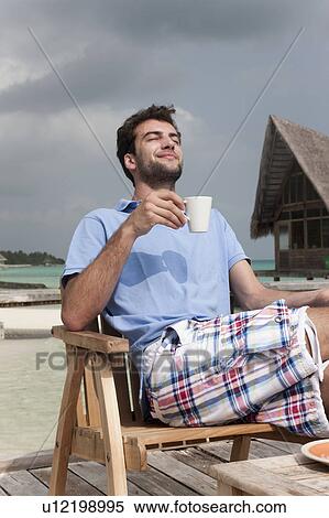 Man drinking coffee on deck at beach View Large Photo Image Stock Photography - Man drinking coffee on deck at beach. Fotosearch