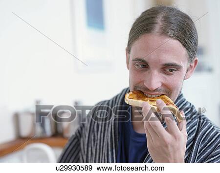 Man eating toast in kitchen View Large Photo Image Stock Photo - Man eating toast in kitchen. Fotosearch