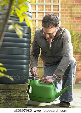 Stock Image - Man filling jug with recycled water. Fotosearch