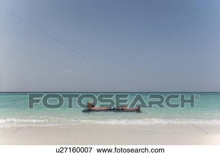 Man floating in water at tropical beach View Large Photo Image Stock Photo - Man floating in water at tropical beach. Fotosearch
