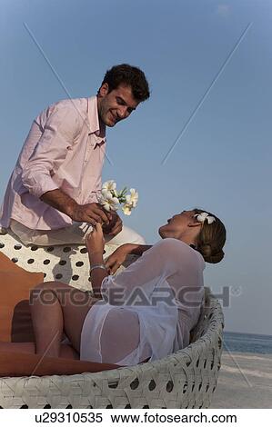 Stock Photography - Man giving girlfriend flowers on beach. Fotosearch