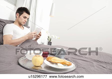 Man having breakfast in bed View Large Photo Image Stock Photo - Man having breakfast in bed. Fotosearch