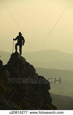 Stock Photo - Man hiking on rocky hillside. Fotosearch