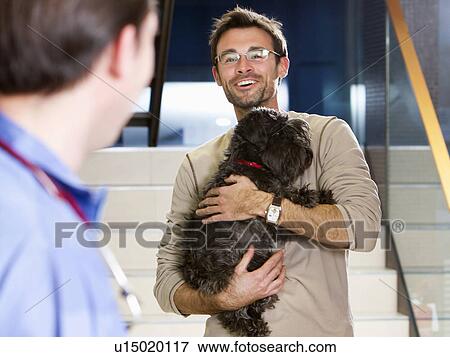 Man holding dog at vet View Large Photo Image Stock Photo - Man holding dog at vet. Fotosearch