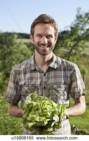 Stock Photography - Man holding head of lettuce outdoors. Fotosearch