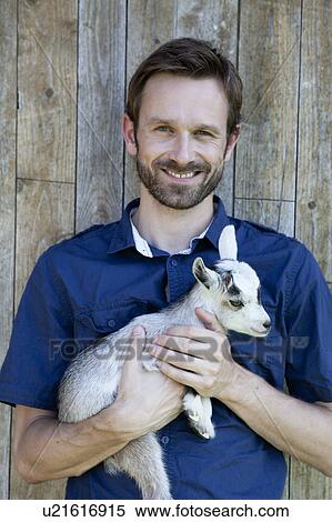 Man holding kid goat outdoors View Large Photo Image Stock Photography - Man holding kid goat outdoors. Fotosearch