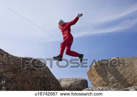 Stock Photo - Man jumping between boulders. Fotosearch