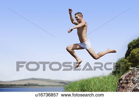 Man jumping off rock into water View Large Photo Image Stock Photo - Man jumping off rock into water. Fotosearch