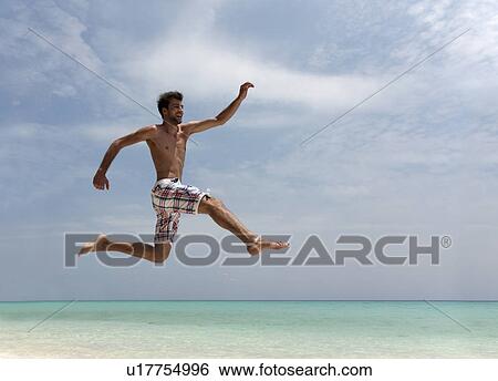 Stock Photograph - Man jumping on tropical beach. Fotosearch