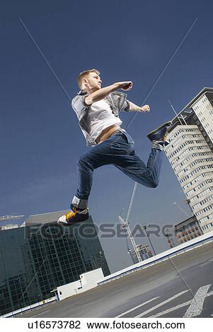 Man jumping on urban rooftop View Large Photo Image Stock Image - Man jumping on urban rooftop. Fotosearch