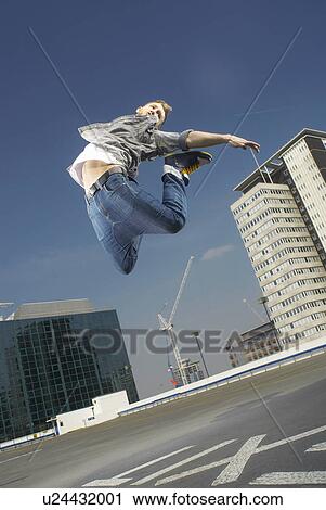 Man jumping on urban rooftop View Large Photo Image Stock Image - Man jumping on urban rooftop. Fotosearch