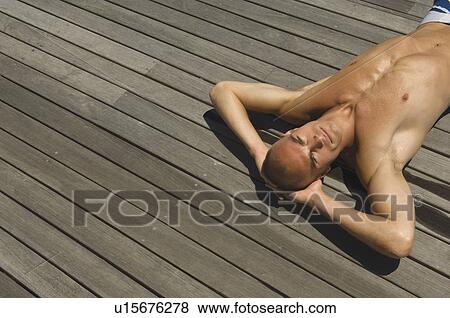 Stock Photo - Man laying on wooden deck. Fotosearch