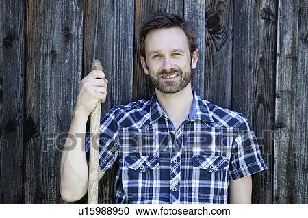 Stock Image - Man leaning against wooden fence. Fotosearch