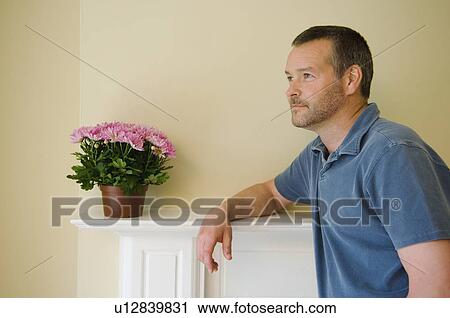 Stock Image - Man leaning on mantle of new home. Fotosearch