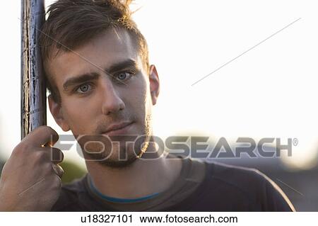 Man leaning on pole outdoors View Large Photo Image Stock Image - Man leaning on pole outdoors. Fotosearch
