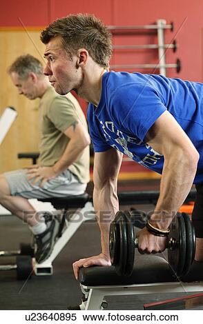 Stock Photography - Man lifting weights at gym. Fotosearch