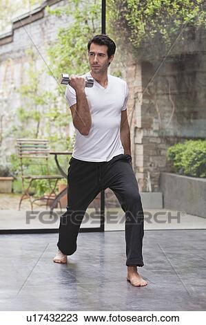 Man lifting weights at home View Large Photo Image Stock Image - Man lifting weights at home. Fotosearch